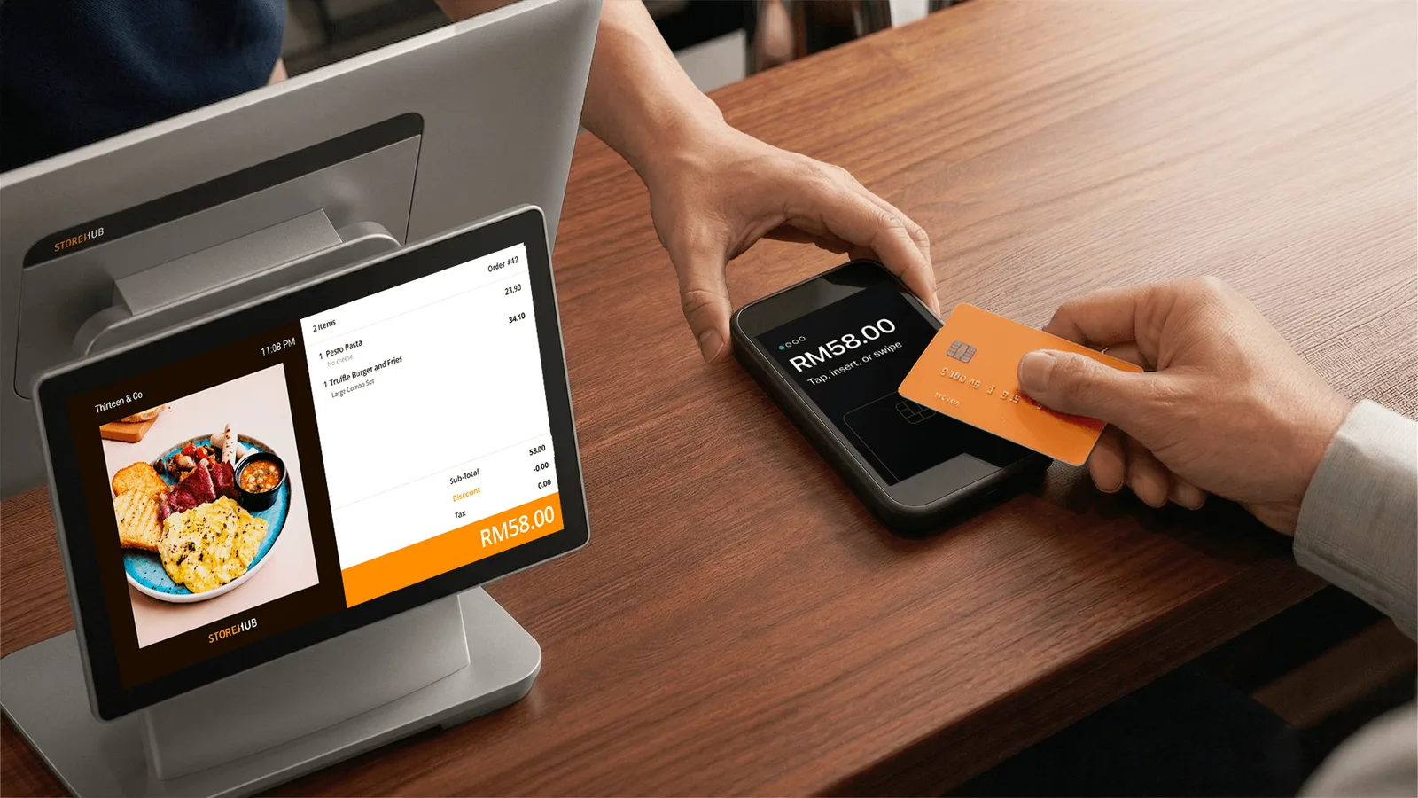 Customer tapping an orange contactless card on a StoreHub Pay terminal at a café counter